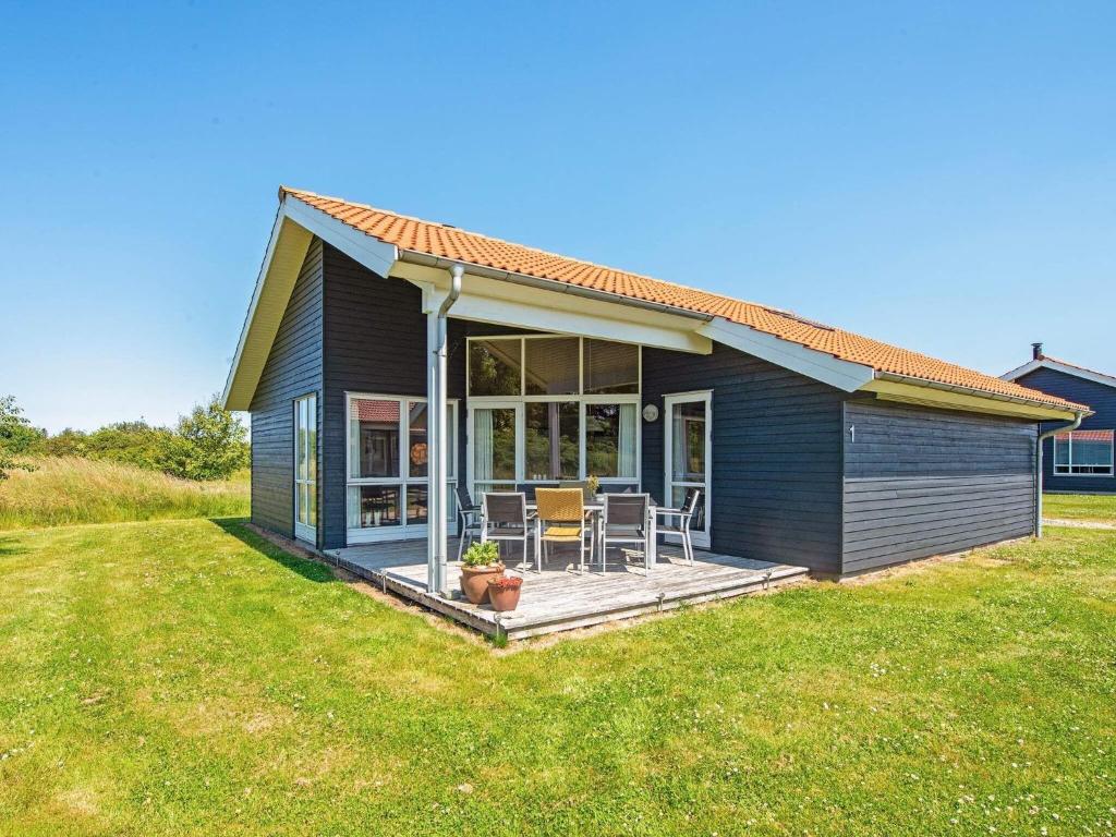 a small house with a deck in a yard at 8 person holiday home in Ulfborg in Fjand Gårde
