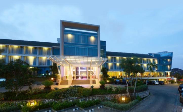 a large blue building with a parking lot in front of it at Emersia Hotel and Resort in Bandar Lampung