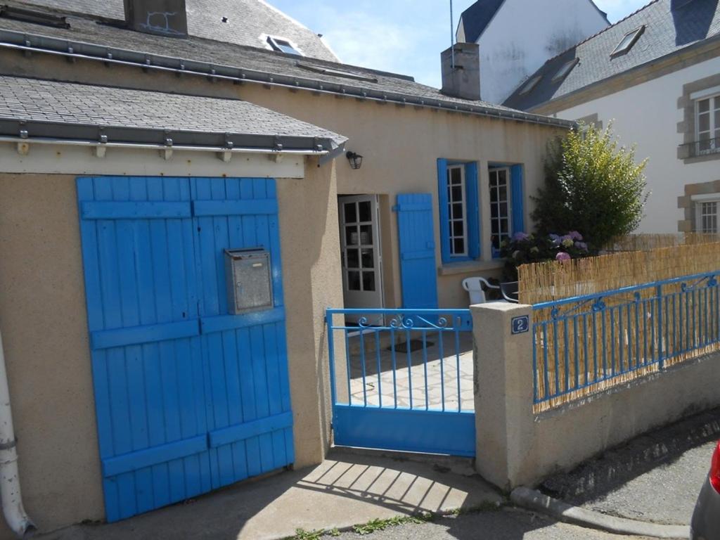 uma porta de garagem azul numa casa com uma cerca em Maison Étel, 3 pièces, 4 personnes - FR-1-397-6 em Étel
