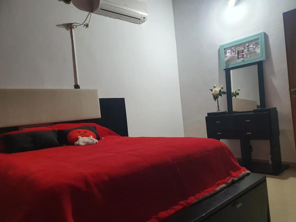 una cama roja con un animal de peluche sobre ella en Uriburu B&B en Resistencia