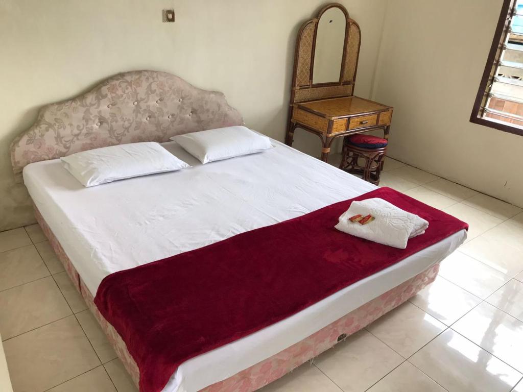um quarto com uma cama grande e uma cadeira em Hotel Miranda at Desa Wisata Berastagi em Berastagi