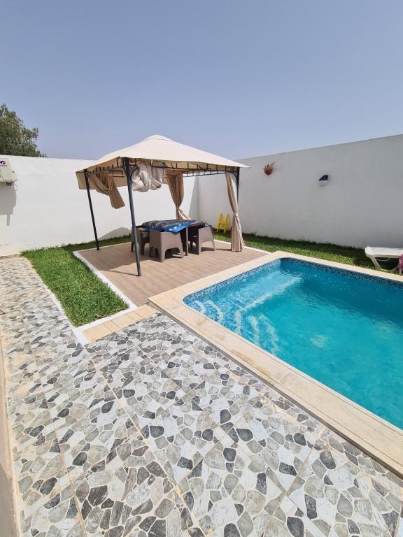 einen Pool mit Sonnenschirm neben einem Haus in der Unterkunft Villa le bonheur 
