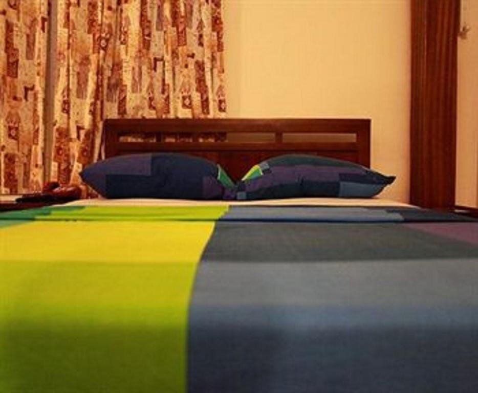 uma cama com um cobertor colorido e almofadas em Calabash Green Executive Apartments em Acra