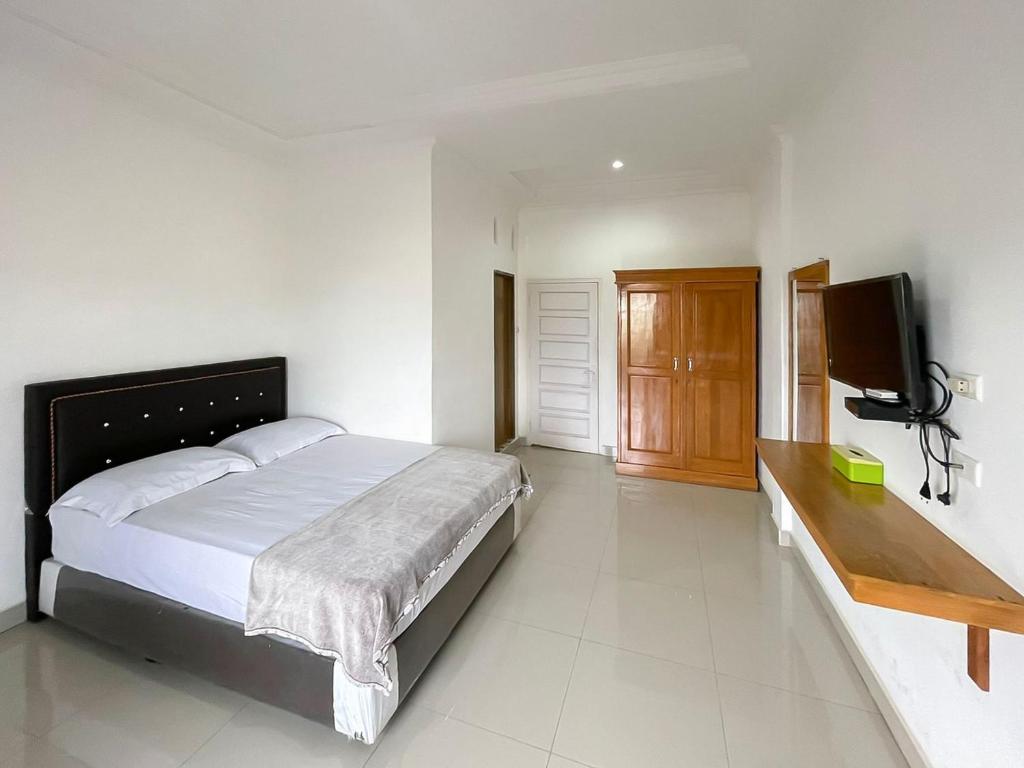 a bedroom with a bed and a flat screen tv at Hotel Lucky 21 Syariah Mitra RedDoorz in Tabahpingin