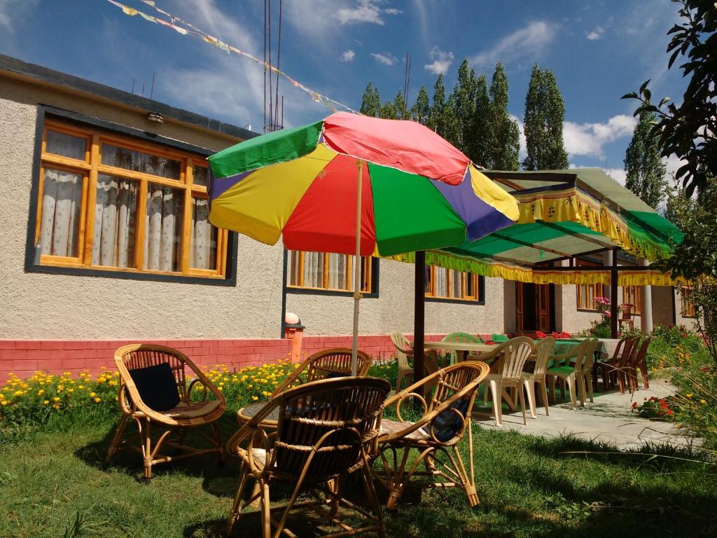 a table and chairs with a colorful umbrella at Rabyang Guest House and Homestay in Leh