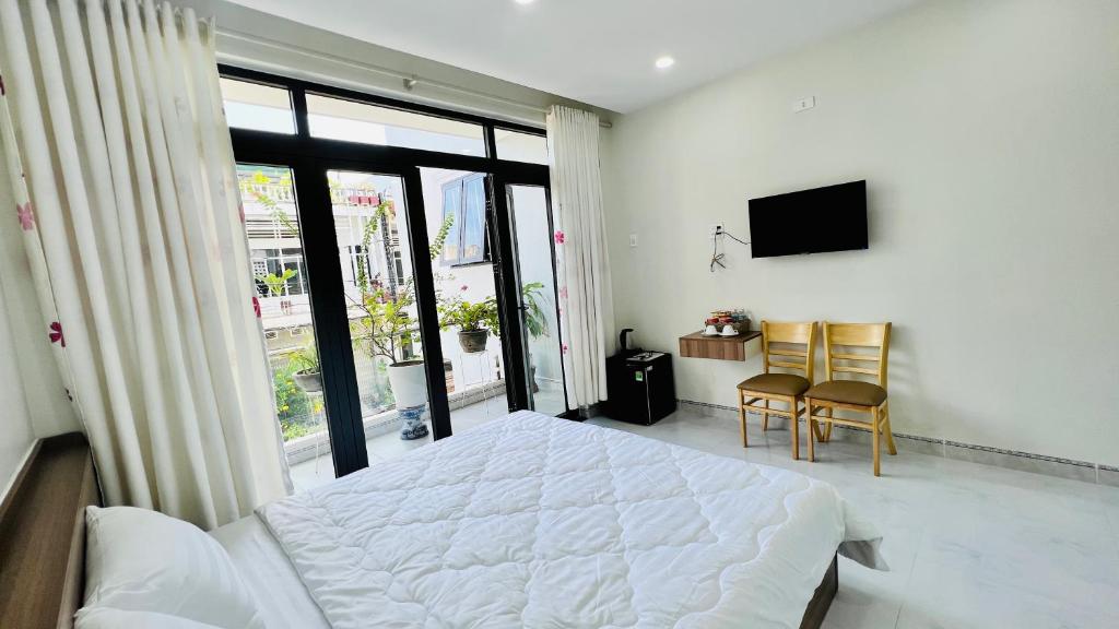 um quarto com uma cama branca e uma televisão em Cô Ba Homestay em Quy Nhon