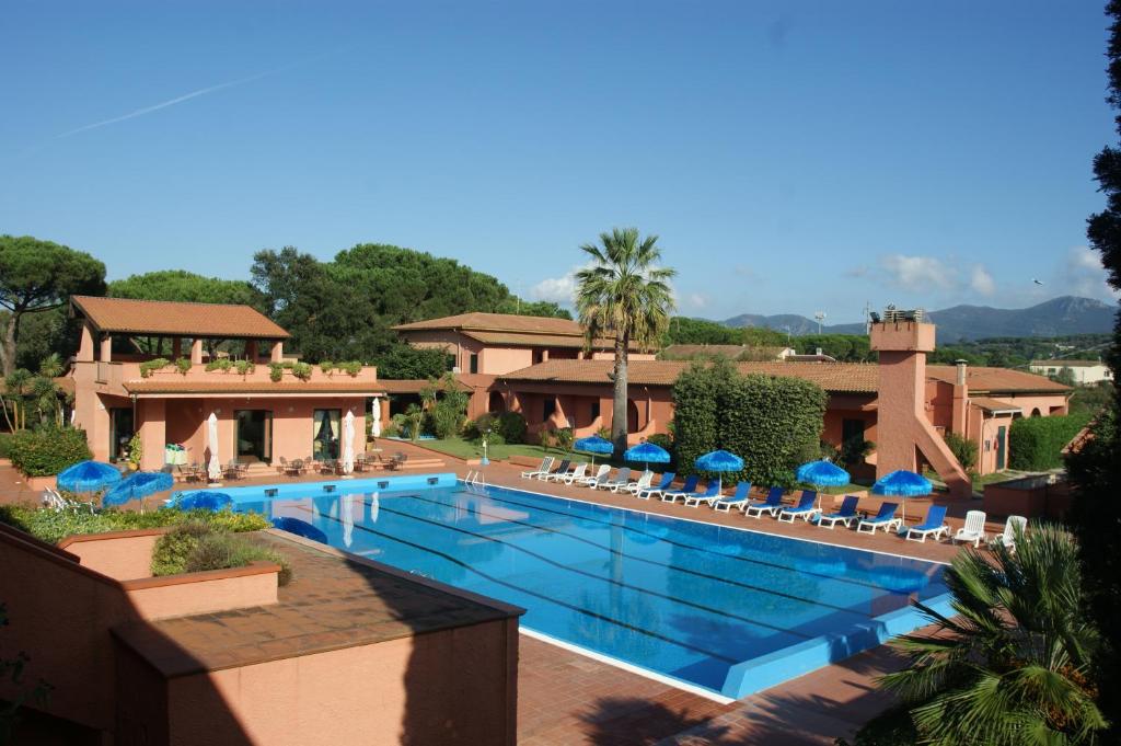 - une piscine avec des chaises et des parasols dans un complexe dans l'établissement Hotel Residence Villa San Giovanni, à Portoferraio