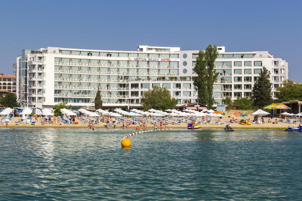 a beach with people and umbrellas and a large building at Hotel Neptun Beach in Sunny Beach