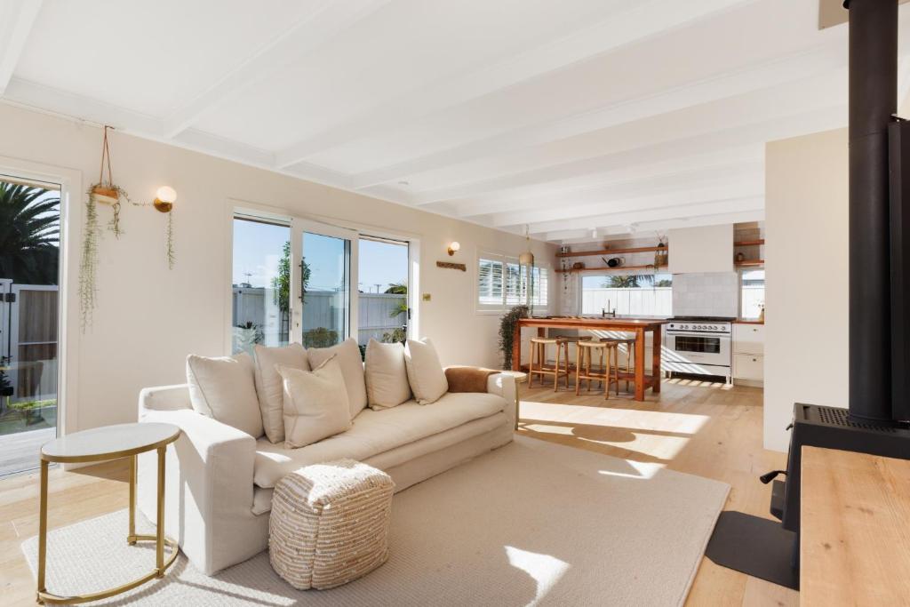 a living room with a couch and a table at The Endless Summer Home - Beach and Town Location in Mount Maunganui