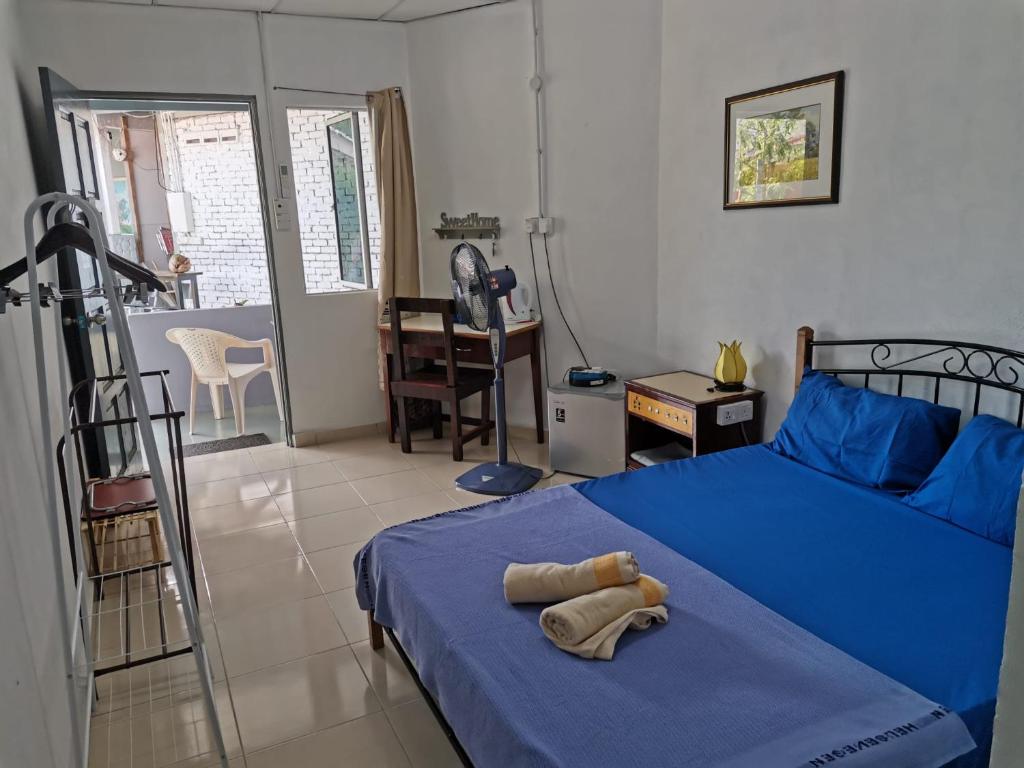 ein Schlafzimmer mit einem blauen Bett und einer blauen Decke in der Unterkunft Langkawi Village Budget Rooms in Pantai Cenang