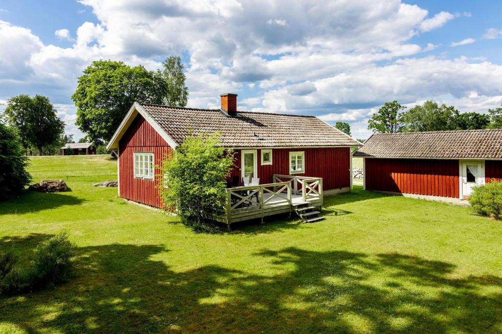 una casa roja con un gran patio delante en Nice cottage in Sjuhult with proximity to Lake Rymmen en Rydaholm