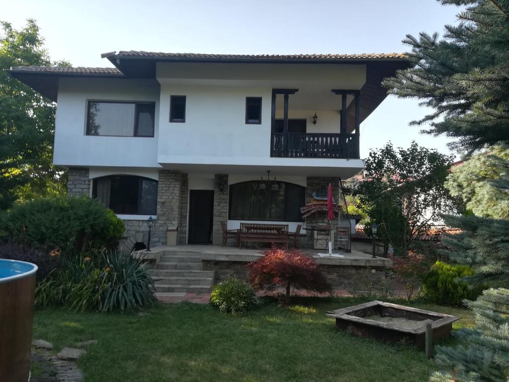 a white house with a balcony and a yard at Гери2 in Arbanasi