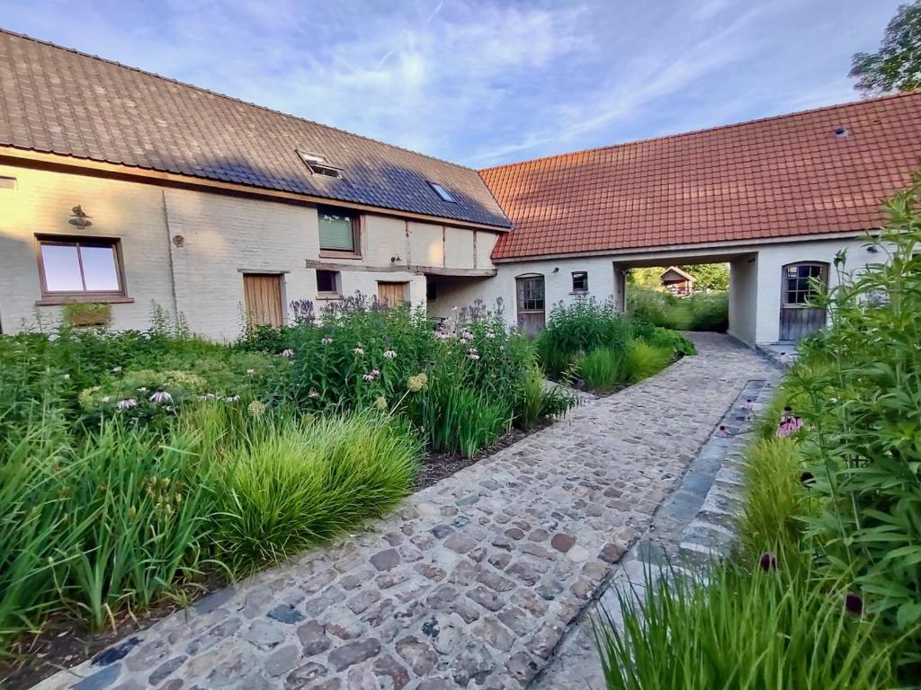 un chemin pavé devant deux bâtiments dans l'établissement Nachtegael Hoekhuis, knusse woning met prachtig vergezicht, à Kluisbergen