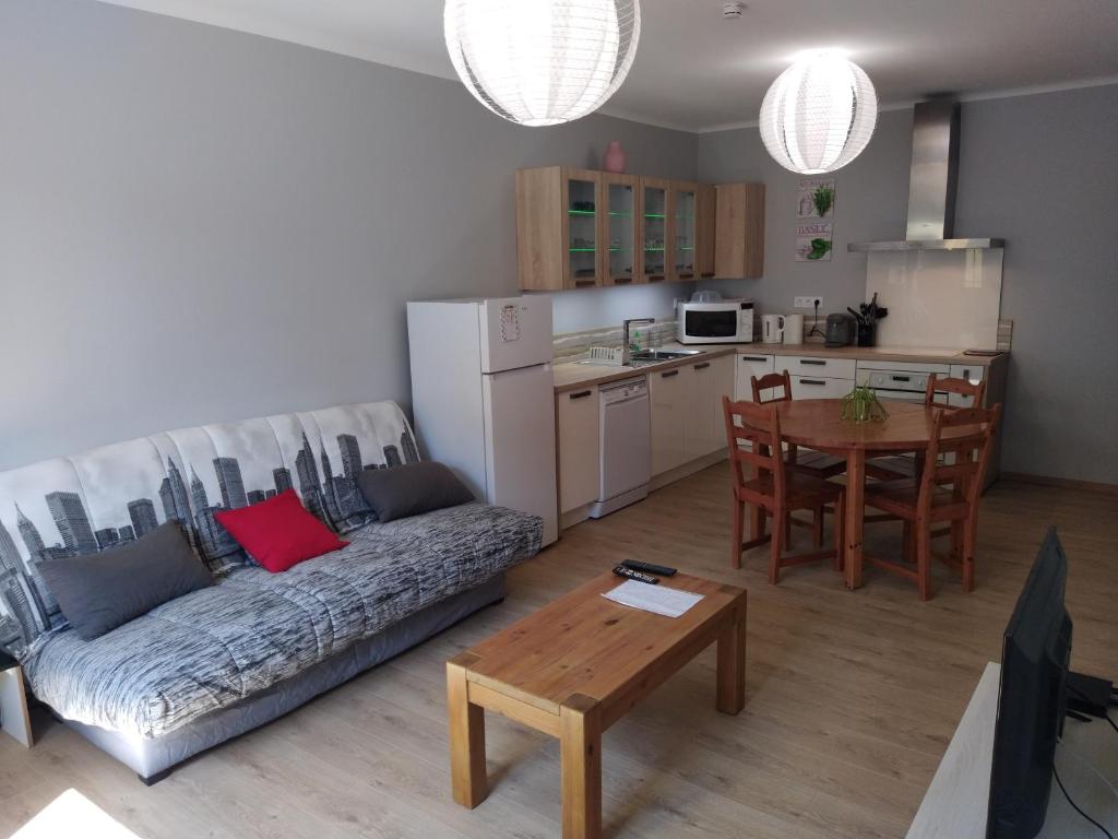 ein Wohnzimmer mit einem Sofa und einem Tisch sowie eine Küche in der Unterkunft Maison de village confortable entièrement rénovée in Saint-Just