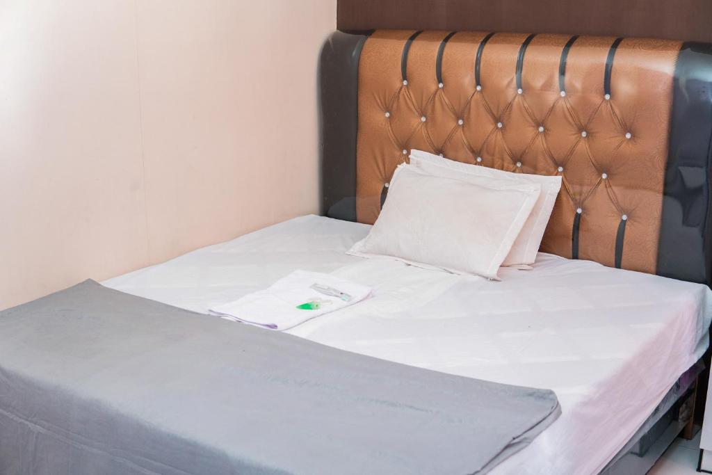 a bed with white sheets and a wooden headboard at Penginapan Sulthan Syariah RedPartner in Takengon