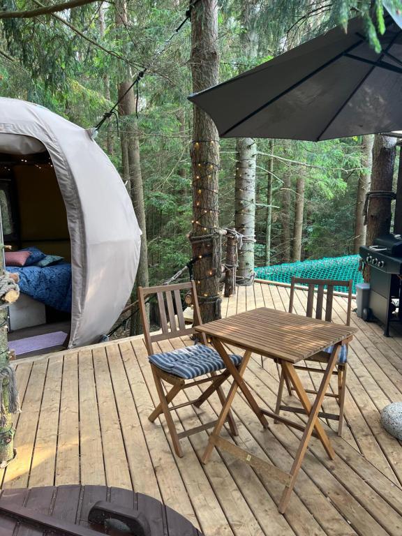 une terrasse en bois avec une table et des chaises ainsi qu'une tente dans l'établissement Nature calls - tree tent 2, à Būtingė