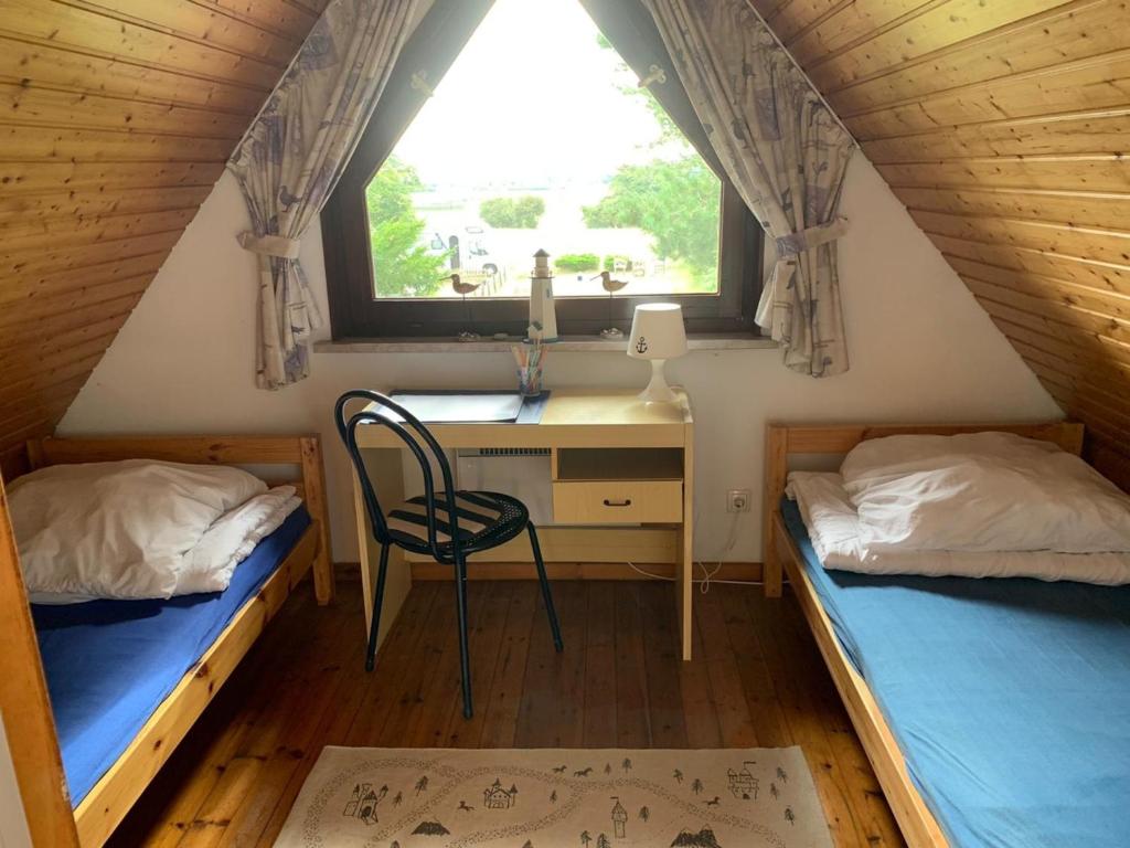 a room with two beds and a desk and a window at Das NURDACH Haus in Heiligenhafen