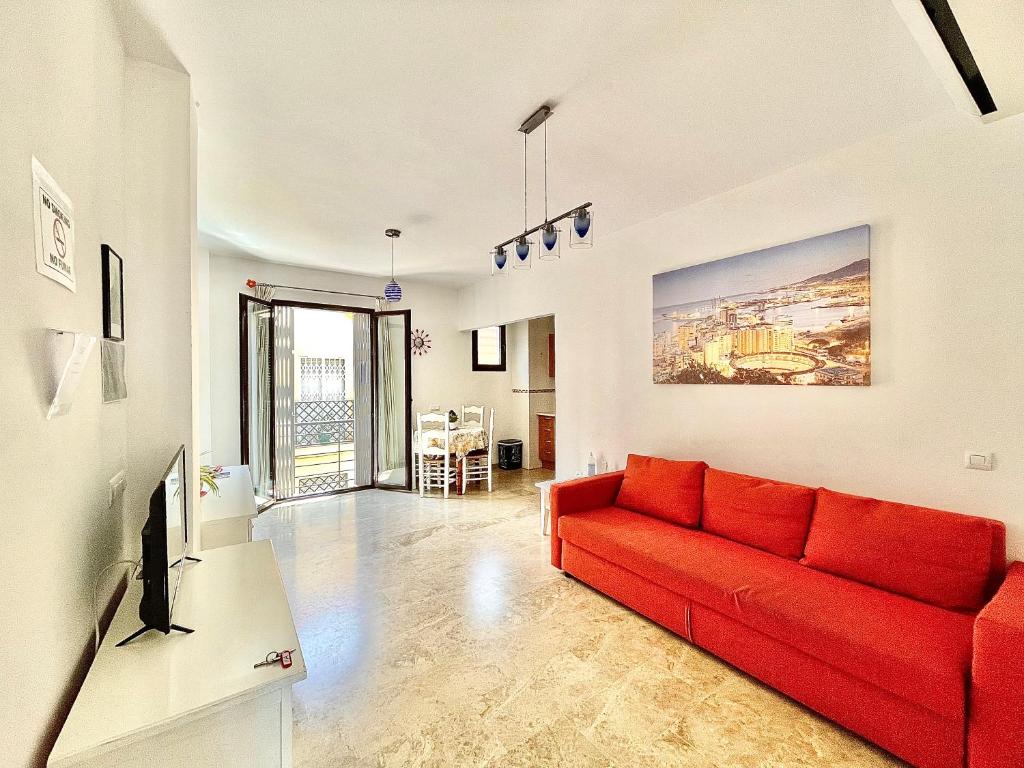 Una sala de estar con un sofá rojo en una habitación. en Jazmín Apartamentos Centro, en Málaga