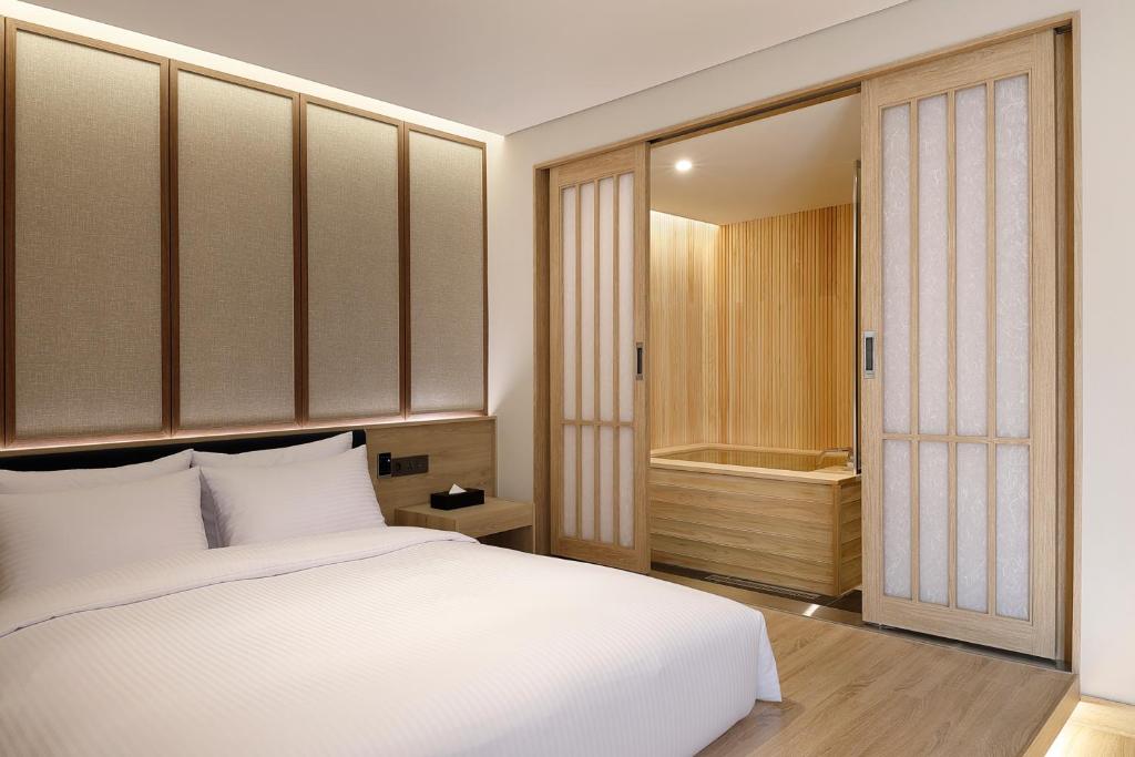 a bedroom with a white bed and a walk in closet at Hotel Foret The Spa in Busan