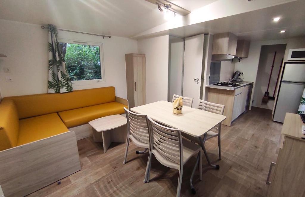 a living room with a yellow couch and a table and chairs at Family&#39;s Camping Le Savoy in Challes-les-Eaux