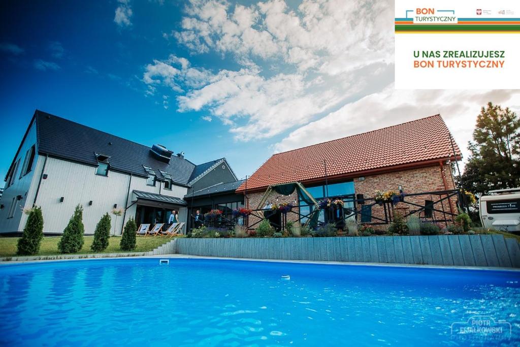 a house with a blue swimming pool in front of a house at Gościniec Pajewo in Pajewo