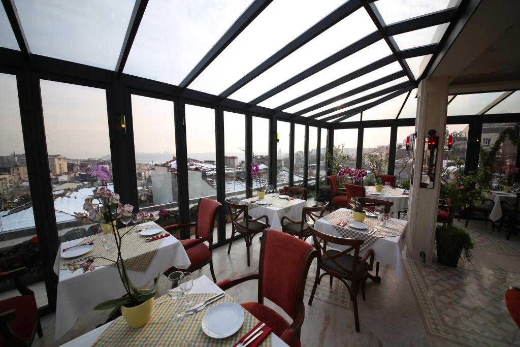 een restaurant met tafels, stoelen en ramen bij Corinne Art & Boutique Hotel in Istanbul