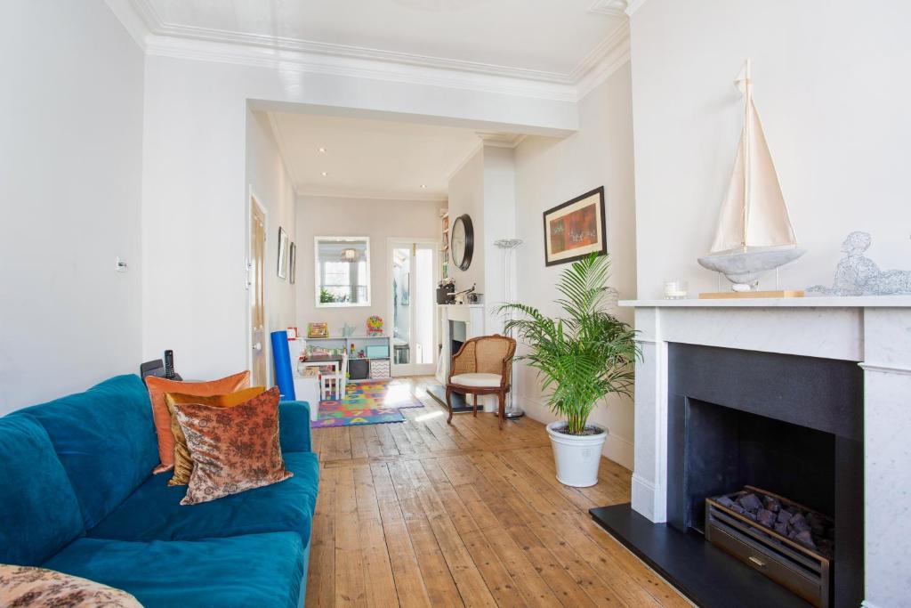 a living room with a blue couch and a fireplace at ALTIDO 3-bedroom family home w/ garden in London