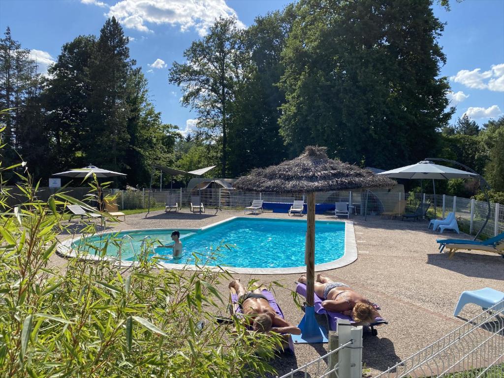 two people laying on chairs next to a swimming pool at Domaine du Château-Epinal in Épinal