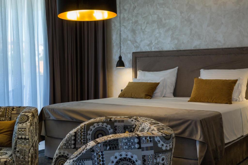 een slaapkamer met een groot bed en een stoel bij Mirabilis Residence II in Zadar