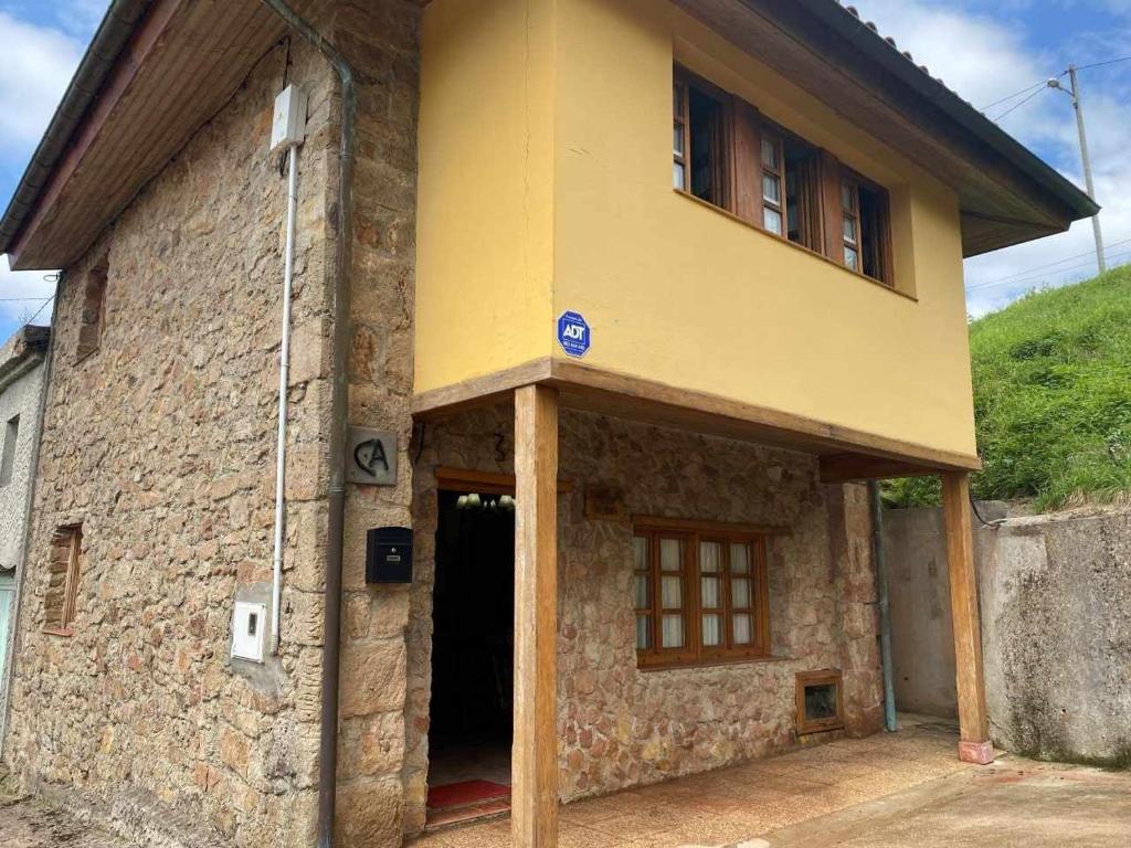 una casa amarilla con una puerta y un edificio en Casa Rural Kiko Asturias, en Bimenes