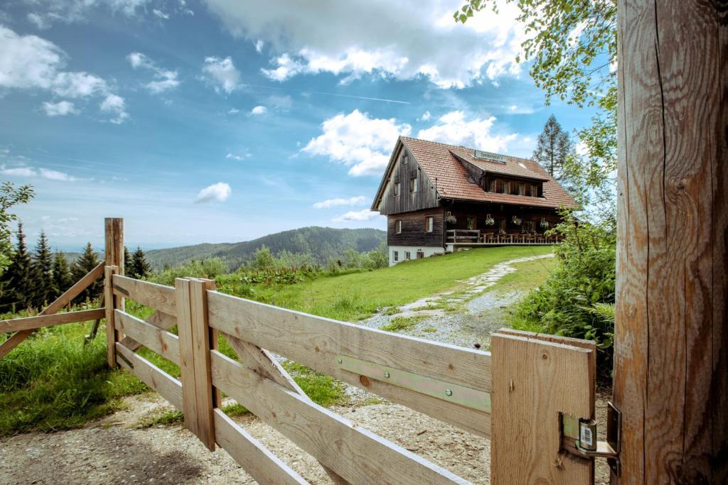 una casa vieja en una colina al lado de una valla en Gamsberg Hütte, en Pack