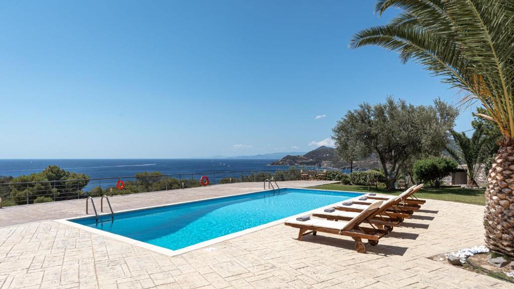 a swimming pool with a bench and a palm tree at Aphaia Villa & Residences Aegina in Agia Marina Aegina