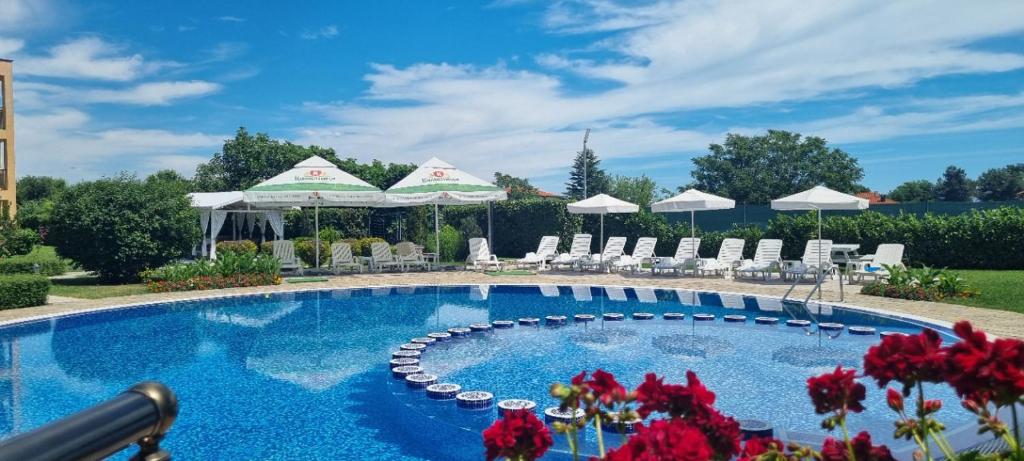 una piscina con sombrillas blancas y flores rojas en Lux Sozopoli Hills Apartments A19 и Studio А13, en Sozopol