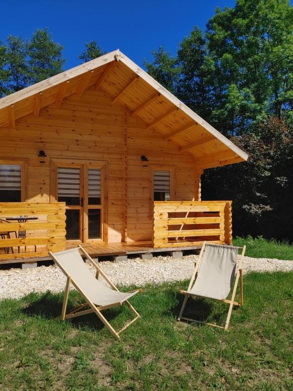 two chairs in front of a log cabin at Dwór Piotra i Pawła- pokoje i domki in Miedzygorze