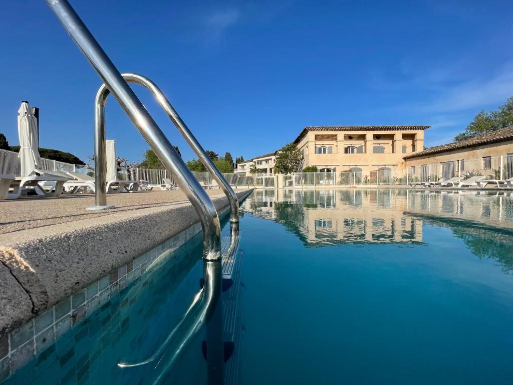 un bassin d'eau avec un bâtiment en arrière-plan dans l'établissement Studio 8 - LES SUITES DE ROBINSON - Résidence avec piscine en bord de Siagne, à Mandelieu-La-Napoule, à Mandelieu-la-Napoule