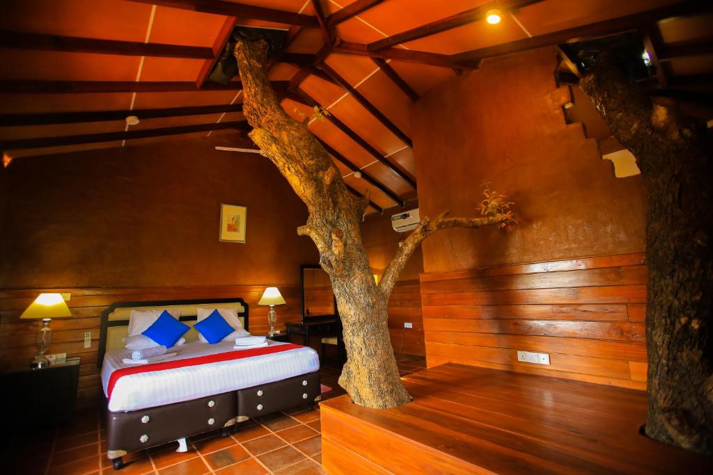 a bedroom with a bed with a tree in it at Jungle Hut Resort Sigiriya in Sigiriya