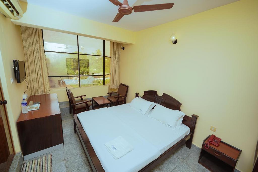 een slaapkamer met een bed, een tafel en een raam bij Hotel oneiro in Trichūr