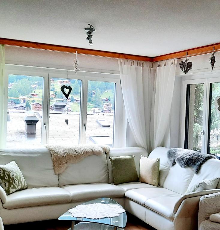 a living room with a white couch and a large window at Bodmen 3 Apartments von Privat in Zermatt in Zermatt