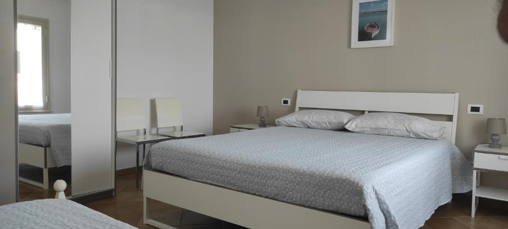 Habitación blanca con cama y espejo en Villa Emilia, en Agrigento