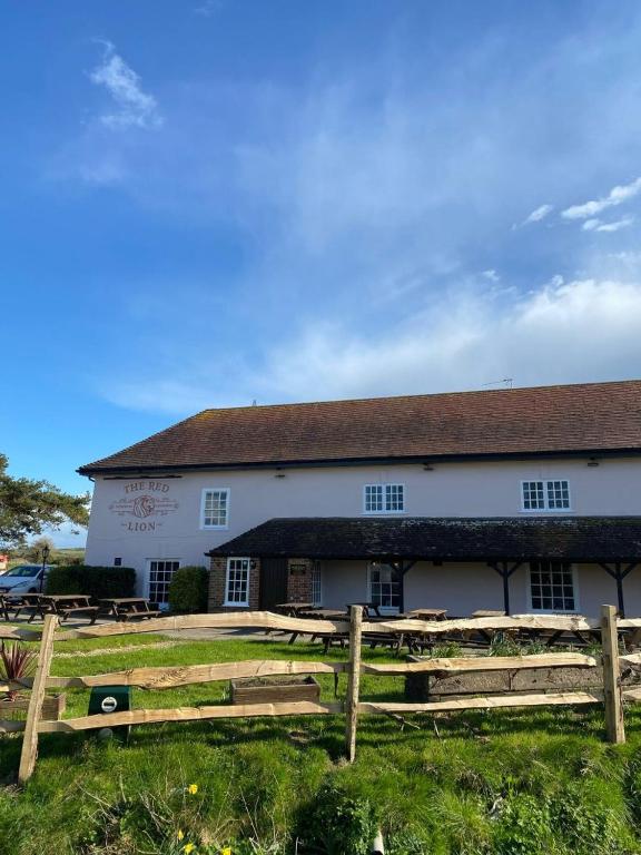 ein weißes Gebäude mit einem Holzzaun davor in der Unterkunft Red Lion in Winfrith Newburgh