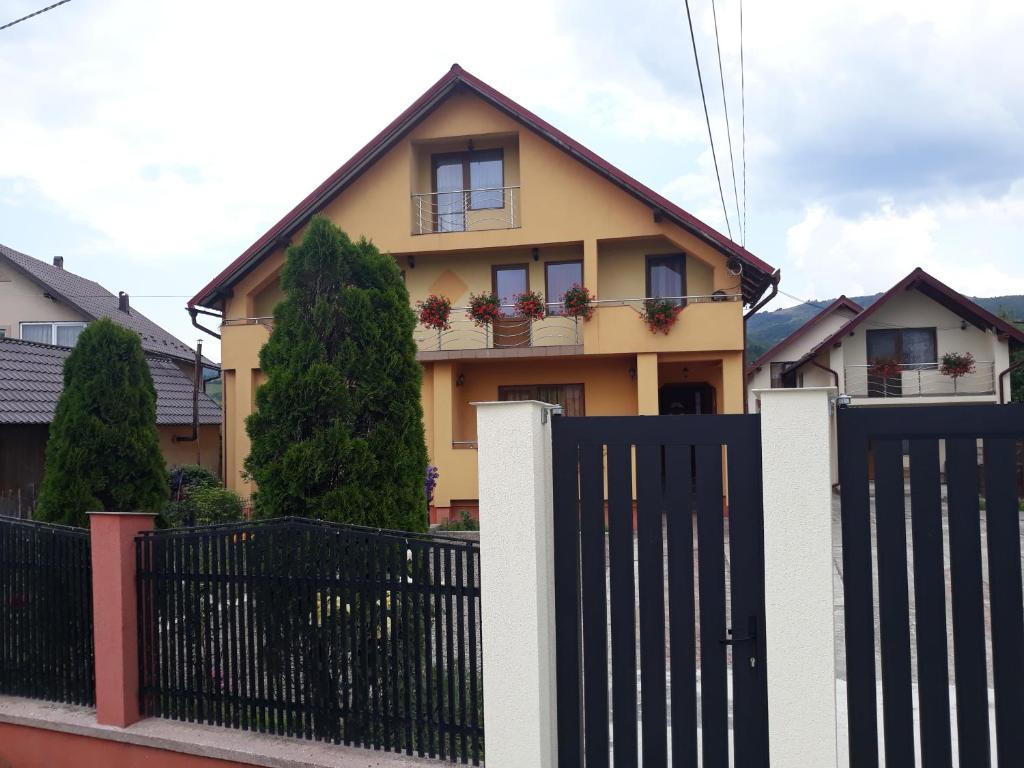 a yellow house with a black fence in front of it at Pensiunea Popan in Şieu