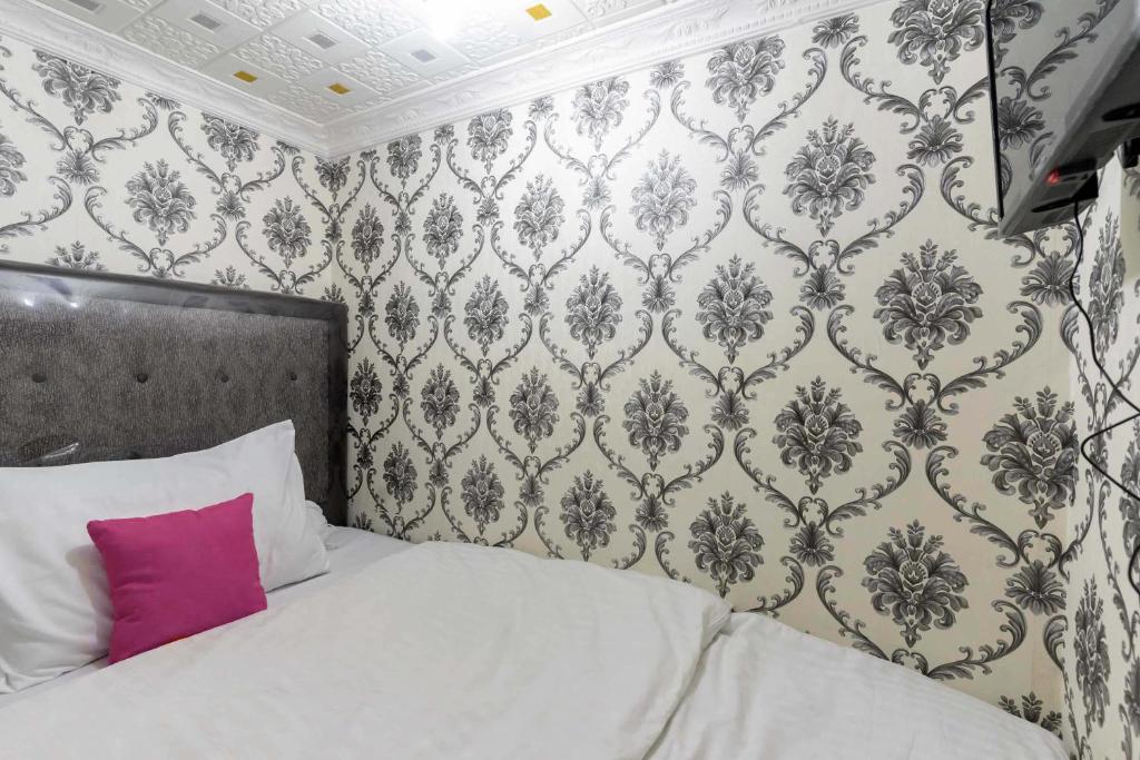 um quarto com uma cama com uma almofada cor-de-rosa em Patent Guest House Syariah RedPartner em Palimbão