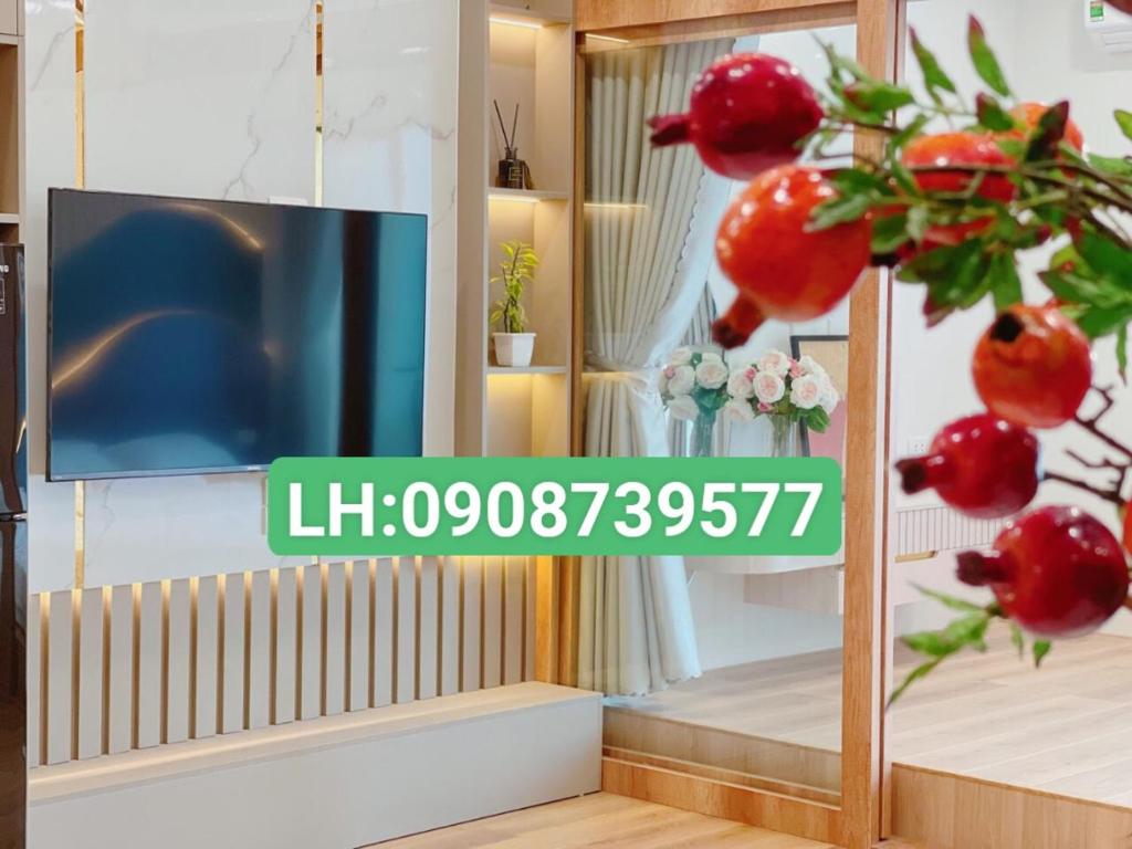 a living room with a tv and a plant with red fruit at TMS Pullman Quy Nhơn Căn Hộ - Xuân Phương Apartment in Quy Nhon