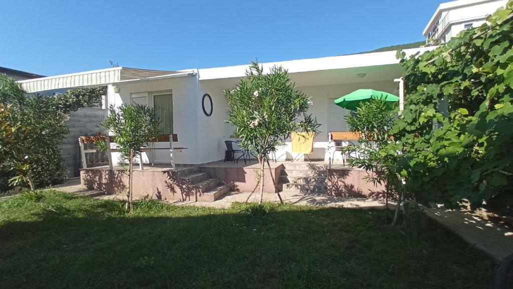 a white house with trees in the yard at Sea Cottage Studios in Budva