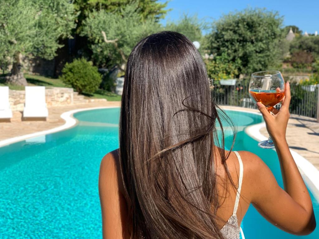 een vrouw met een glas wijn naast een zwembad bij TENUTA MONTANARO in Locorotondo