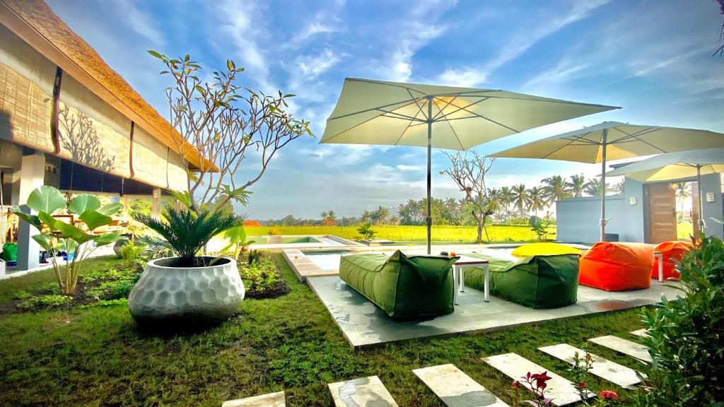 een patio met een tafel, 2 stoelen en een parasol bij Villa Sawah Ramah in Ubud