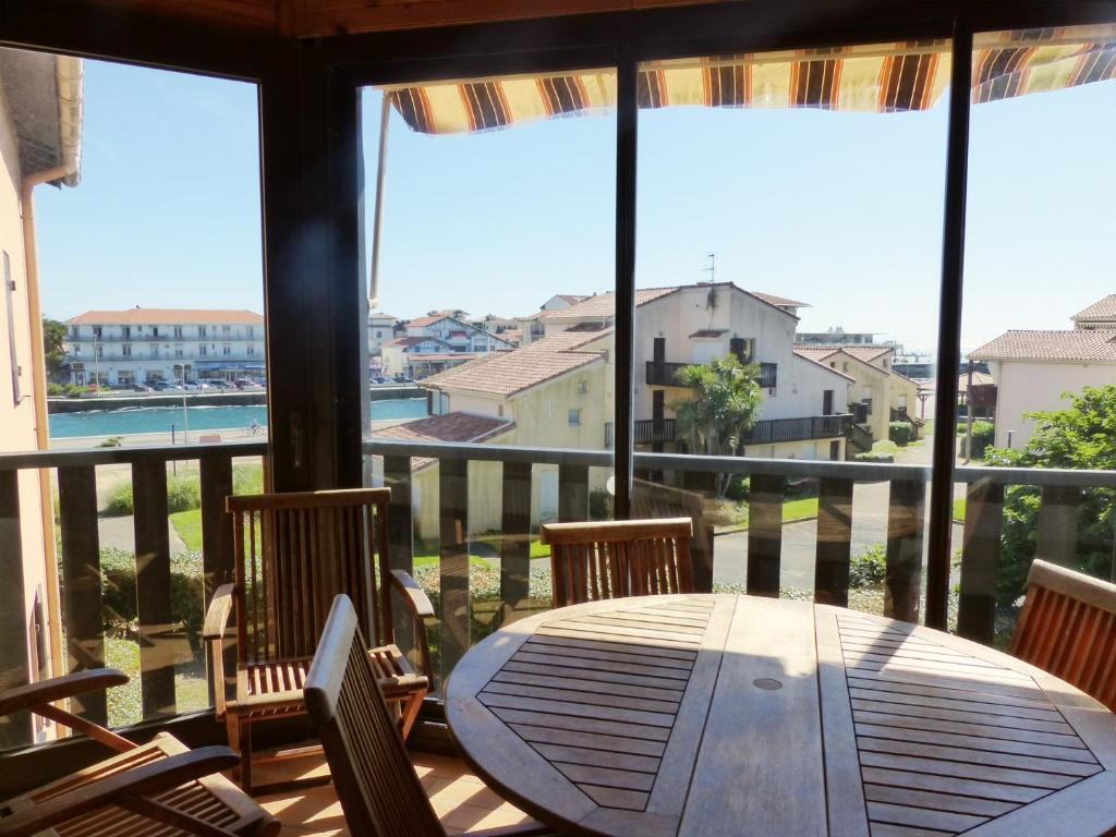 a wooden table and chairs on a balcony with a view at Appartement Avec Piscine En Copropriete Pour 6 Personnes- Residence Notre-Dame Du Port in Capbreton