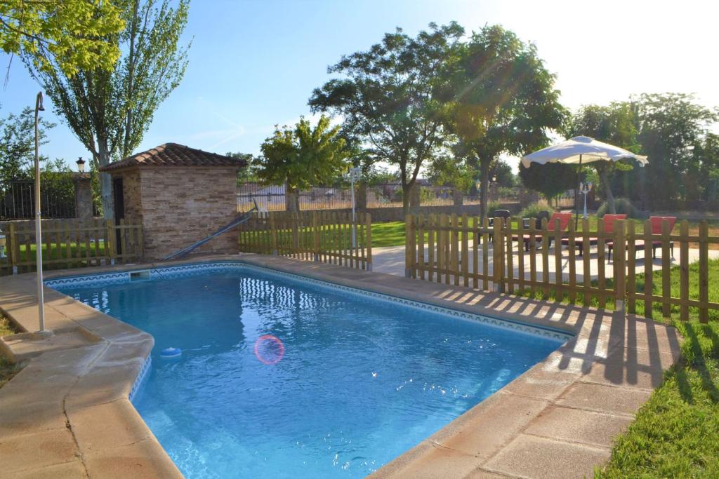 a swimming pool in a yard with a wooden fence at Casa Rural Villa Herrera in Fernancaballero