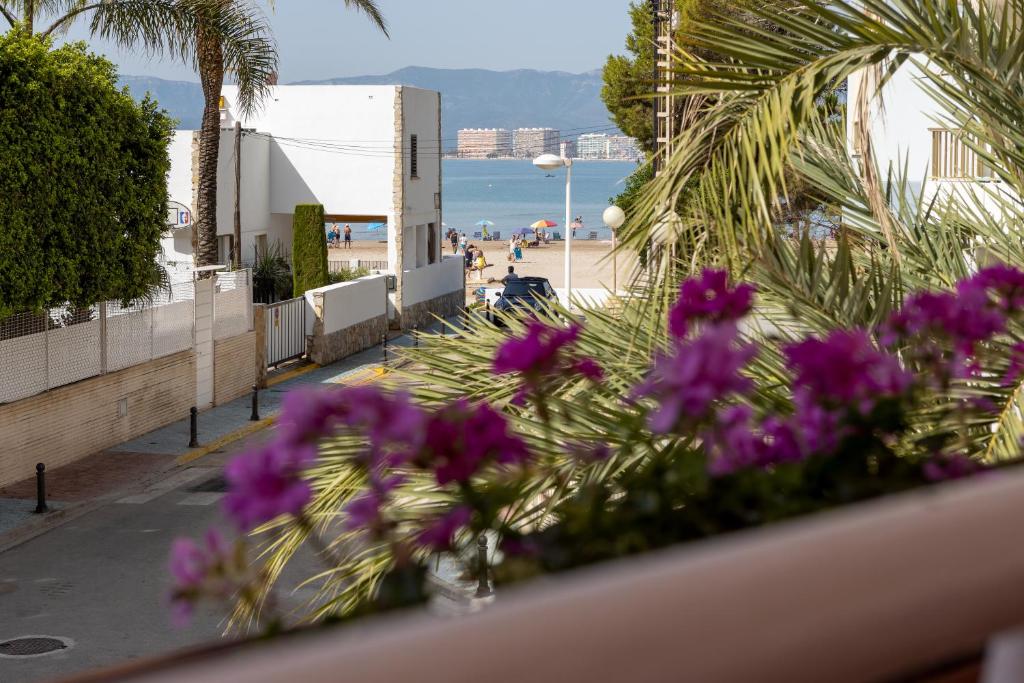 einen Balkon mit lila Blumen und einem Strand in der Unterkunft CHALET VILLA Los HIPOCAMPOS in Faro de Cullera