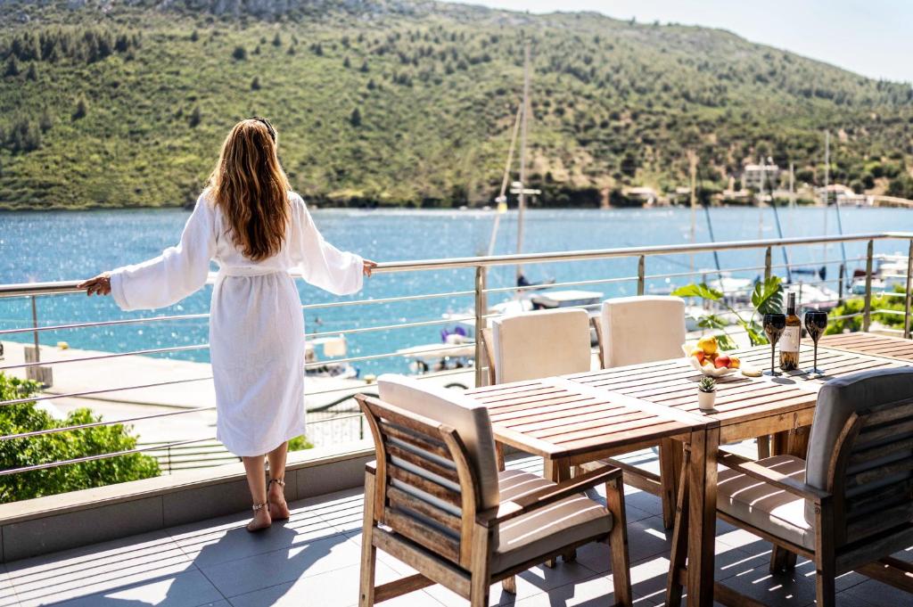 a woman in a white dress standing on the deck of a boat at ANASSA PORTO KOUFO Sea front suites in Porto Koufo